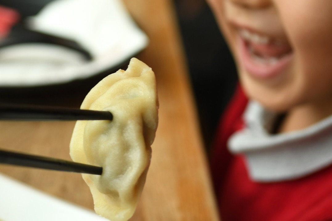 A close up of a child’s mouth about to eat a dumpling from Dough Zone in Seattle’s international district best eats for families