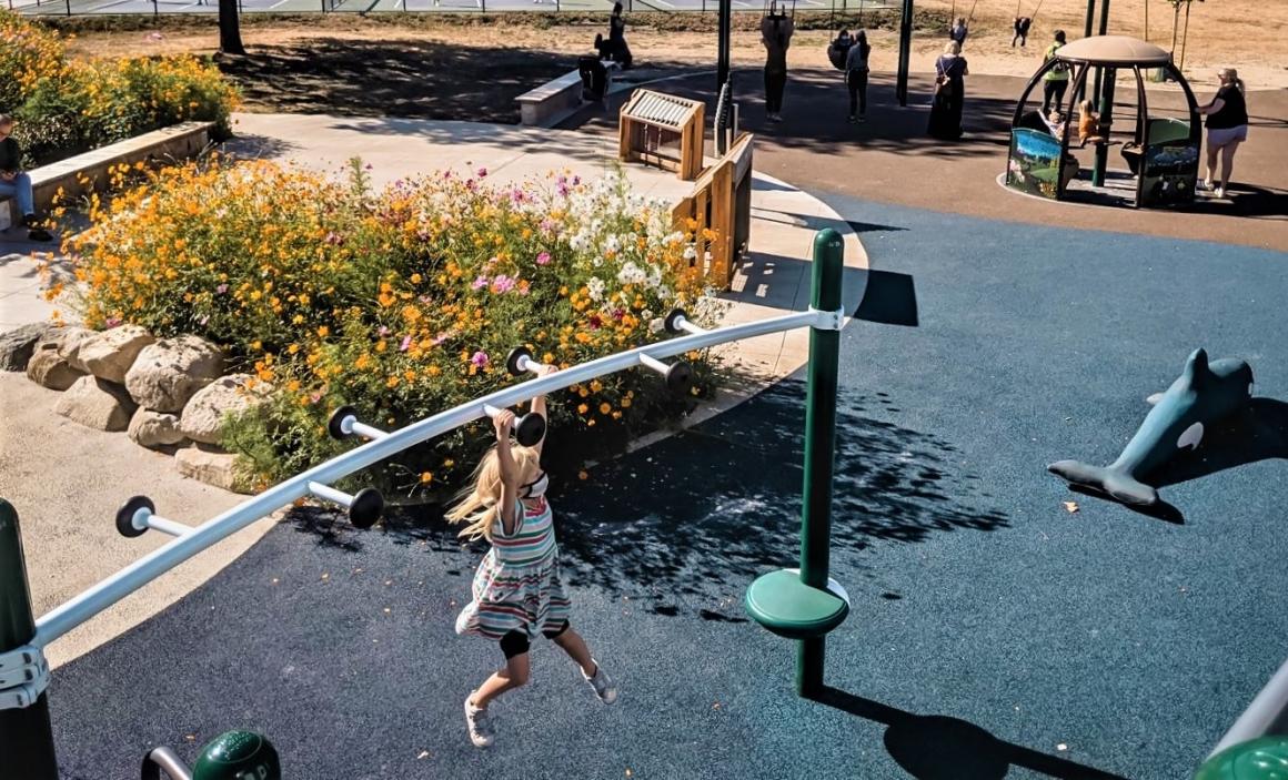 Girl swinging on monkey bars at new ferry boat playground on Bainbridge Island near Seattle kids and families