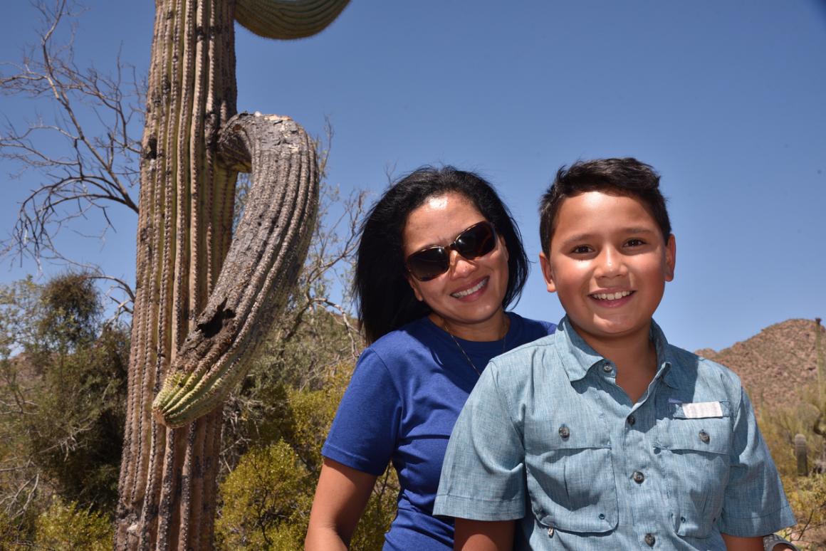 A happy mom in sunglasses and 11-year-old son pose with a saguaro cactus in Arizona; Phoenix is among best sunny destinations one flight away from Seattle