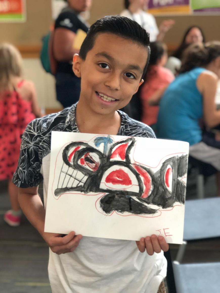 Young boy proudly showing his painting of an orca whale