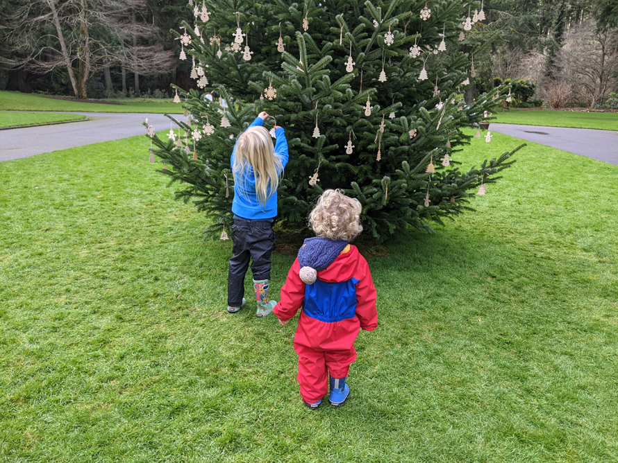 kids hanging ornaments on an outdoor christmas tree