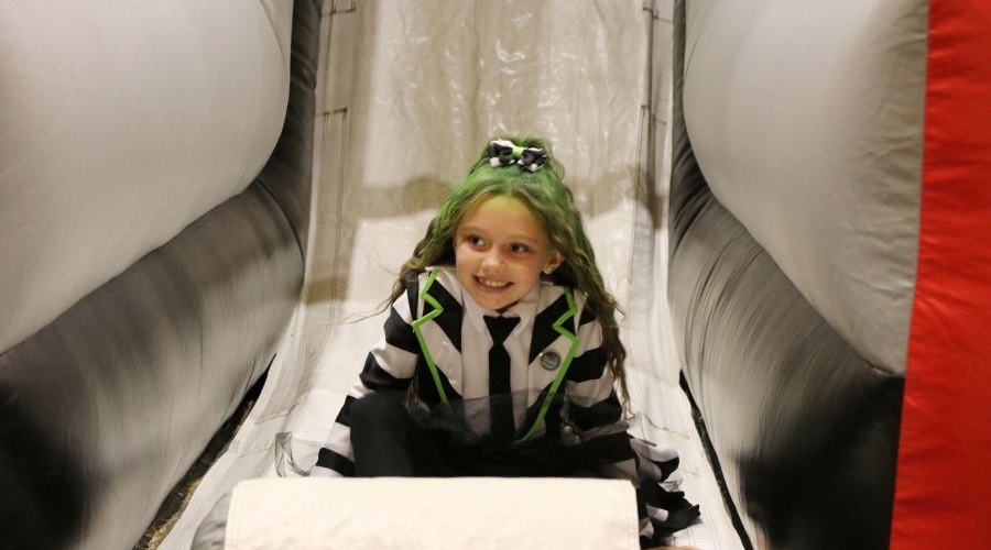 Girl dressed in Halloween costume on inflatable slide at SeaTac's Great Pumpkin Halloween night.