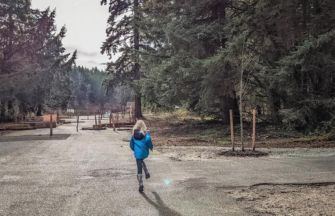 Young girl in blue jacket running on paved pathway at updated Swan Creek Park in Tacoma