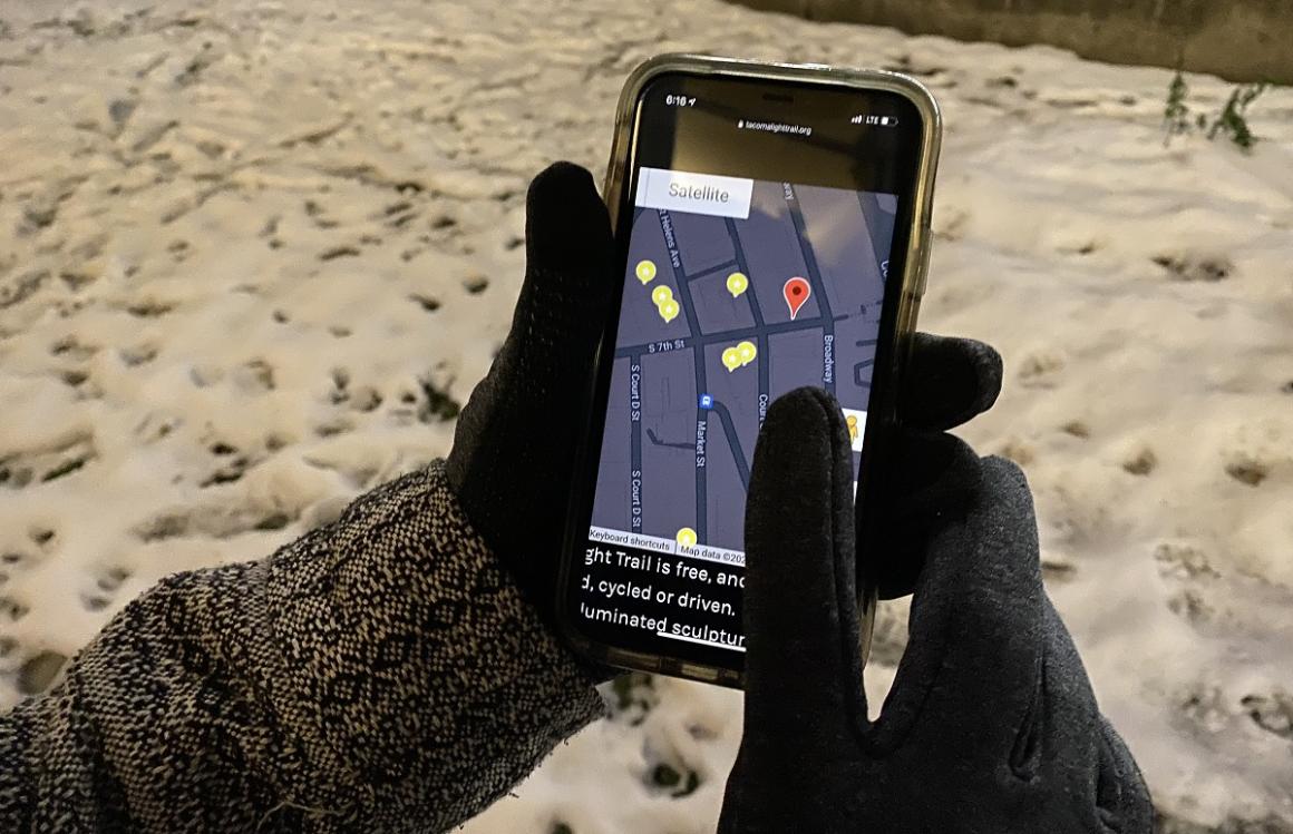 View of hands holding a phone showing a map of stops along the Tacoma Light Trail winter time fun for families