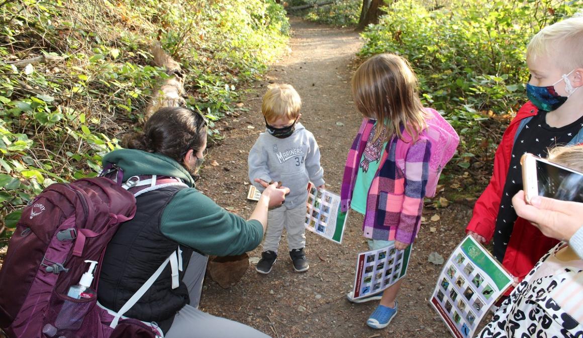 Kids holding field guides on the trail at Tacoma Nature Center guided family nature experience