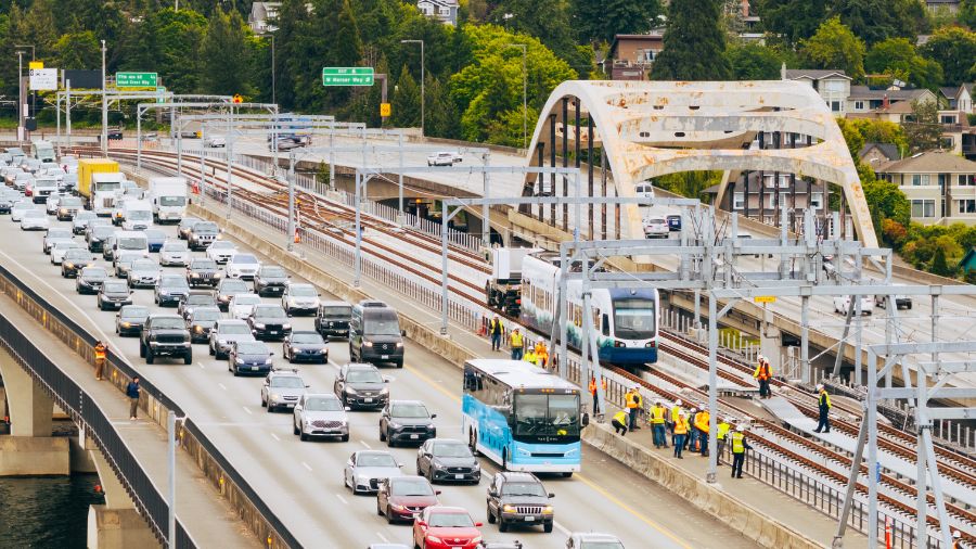 Image of train crossing bridge next to traffic