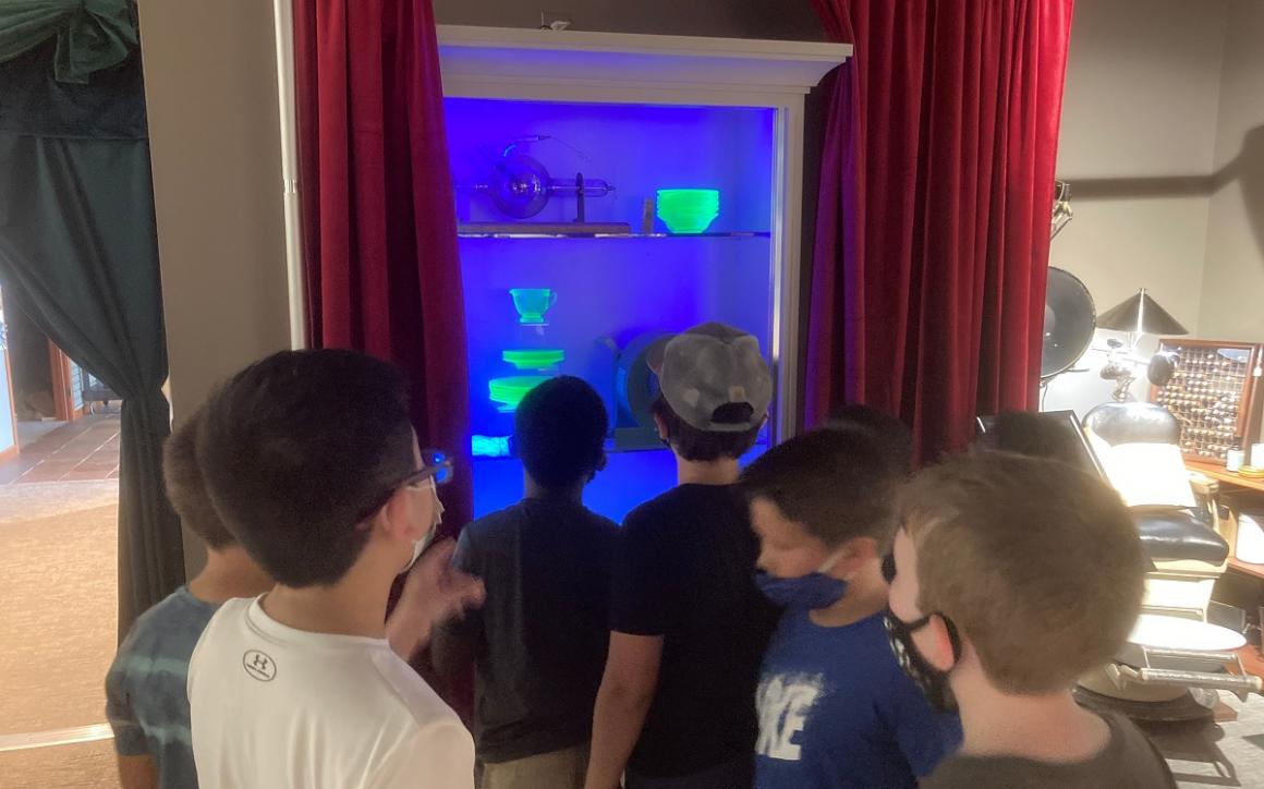 Kids looking at uranium glass dishes glowing when a blacklight is activated