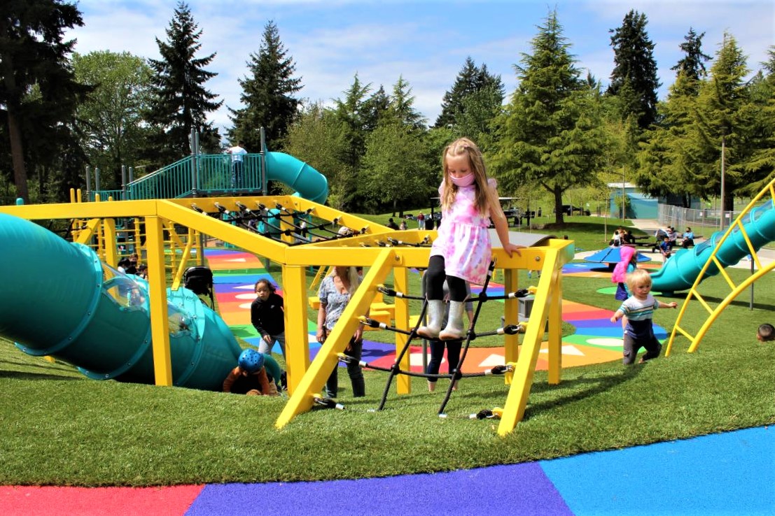 Girl on yellow cargo net climber at new West Fenwick Park playground in Kent near Seattle