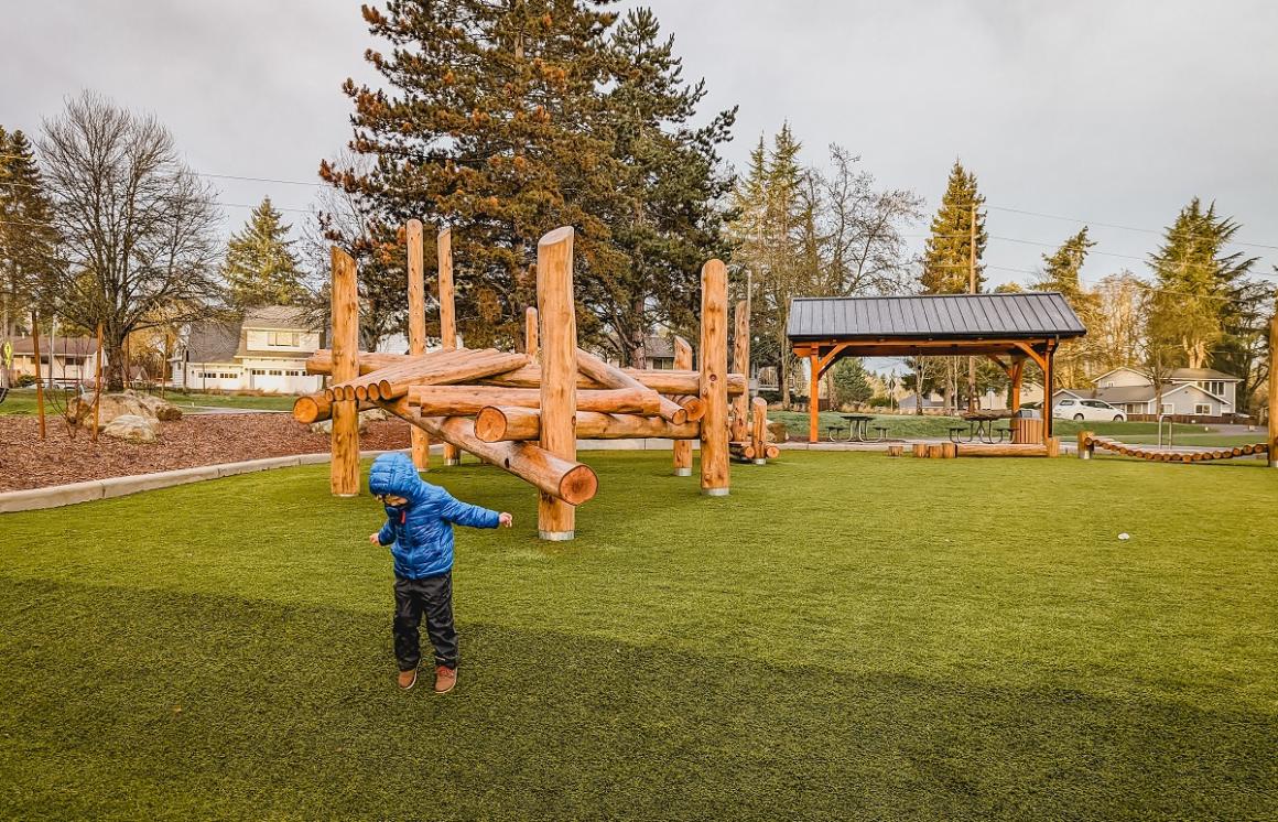 Boy playing on new log play structures at playground at Westside Park in Redmond Washington