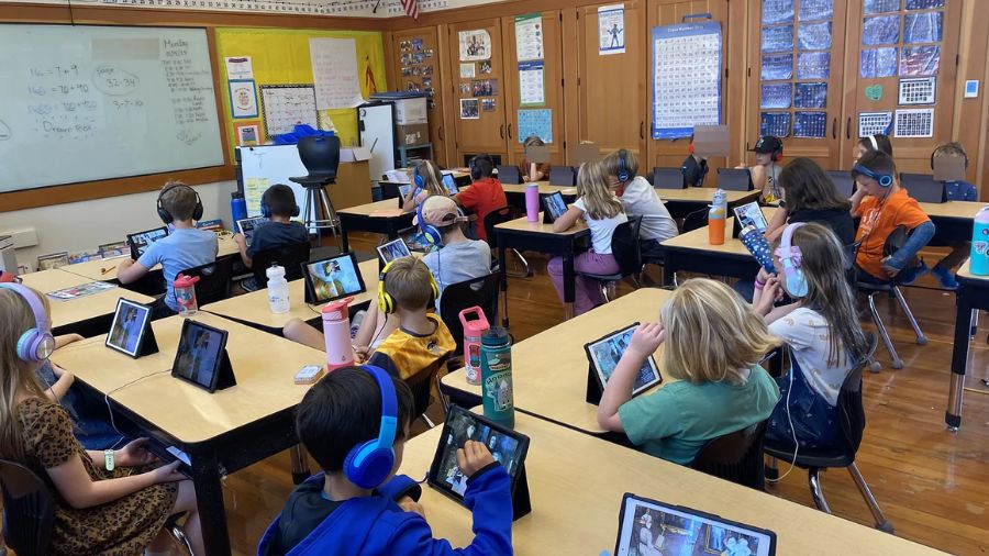 a room full of 7-year-olds with headphones and iPads