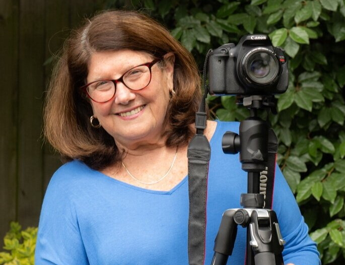 Margot Kravette holding a camera on a tripod