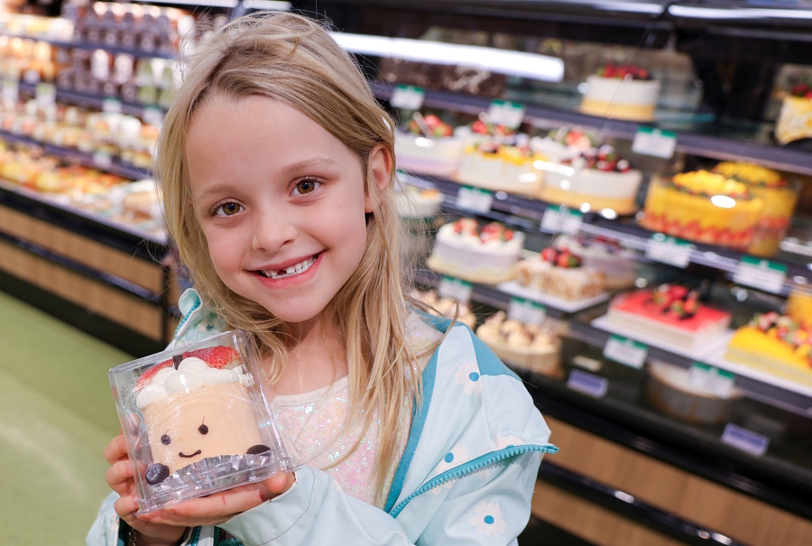 little girl holding a cake with a smile face at T&T market