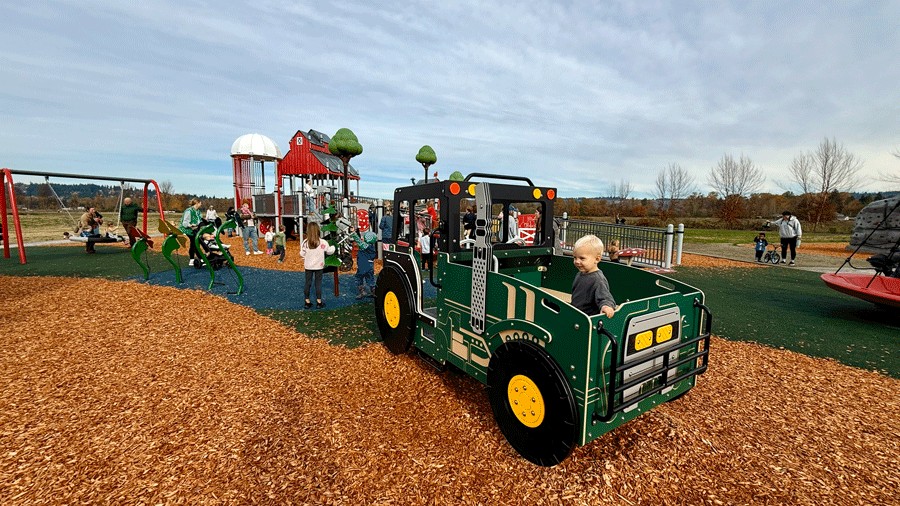 farm-themed van lierop park playground with a jeep and barn-themed structures