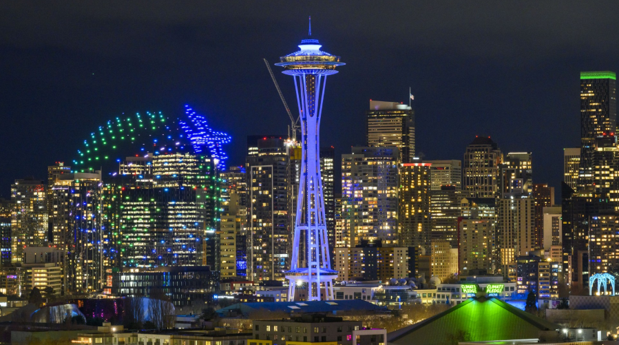 The Seattle Space Needle is lit up for New Year's accompanied by drone lights.
