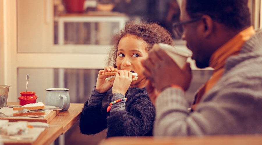 A girl is eating lunch with her father for Black History Month.