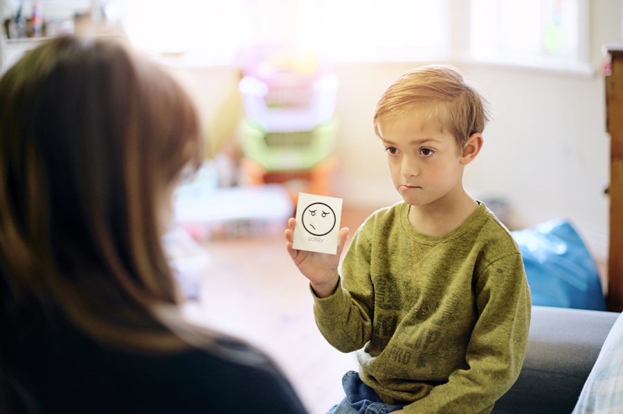 Boy holding up a card to identify his emtions