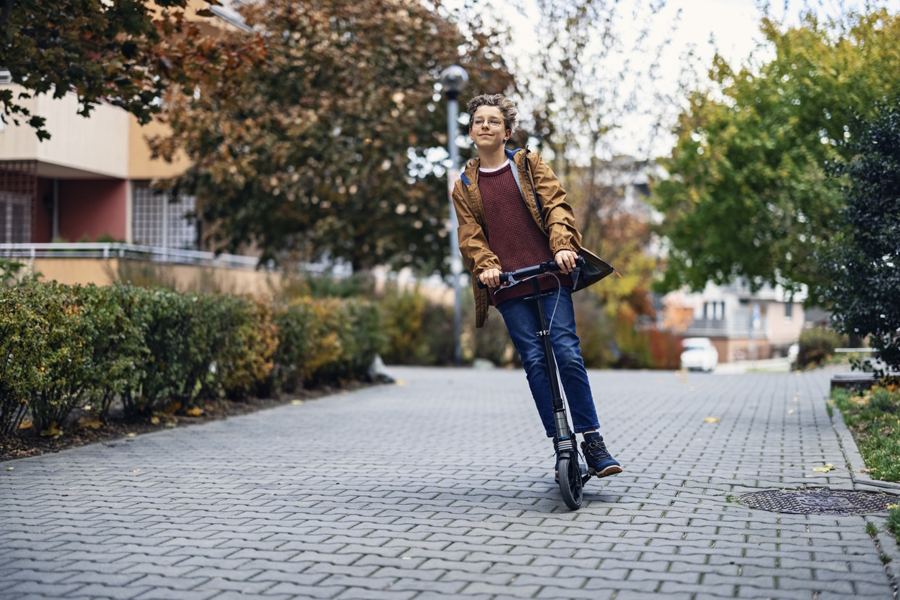 teen boy riding an electric scooter with no helmet
