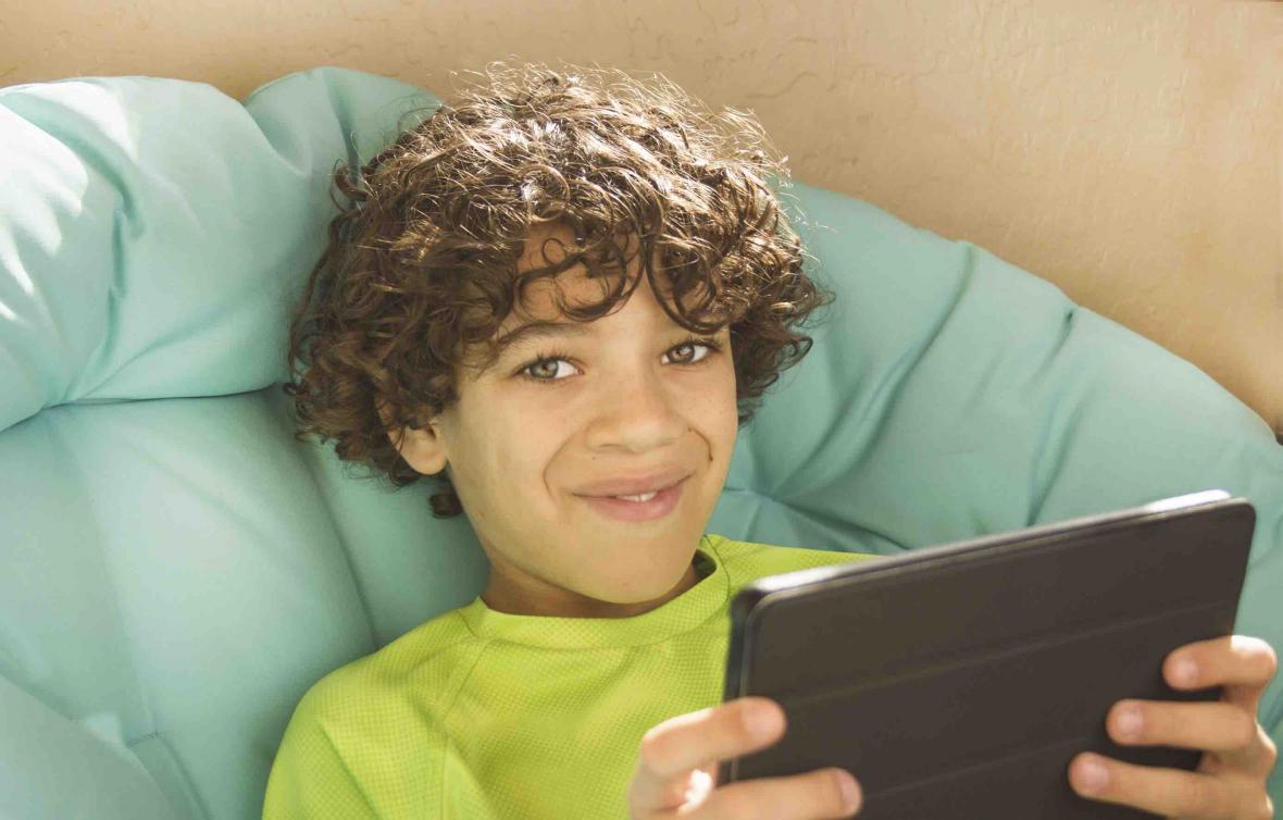 Curly-haired boy playing on tablet