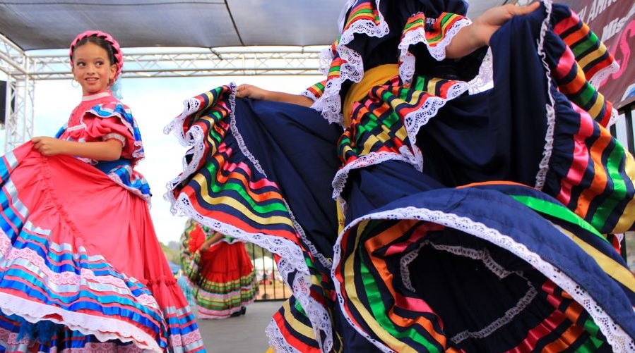 A girl in festive dress dancing at a Hispanic Heritage Month celebration.