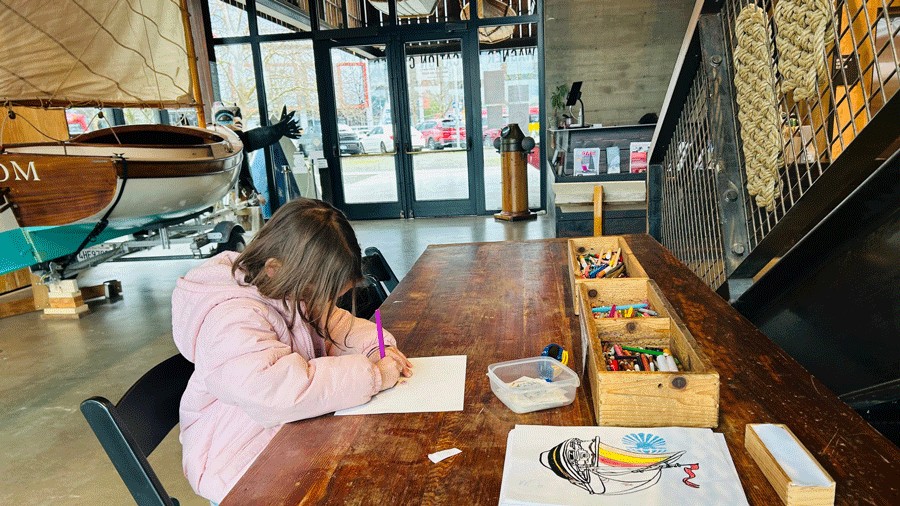 young girl coloring at an activity station inside the Center for Wooden Boats