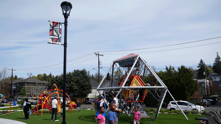 Cheryl Chow Park lampposts with community artwork, with kids playing on the playground