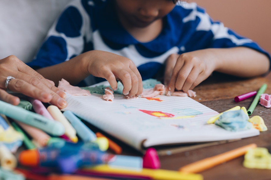 child decorating a book they made at home