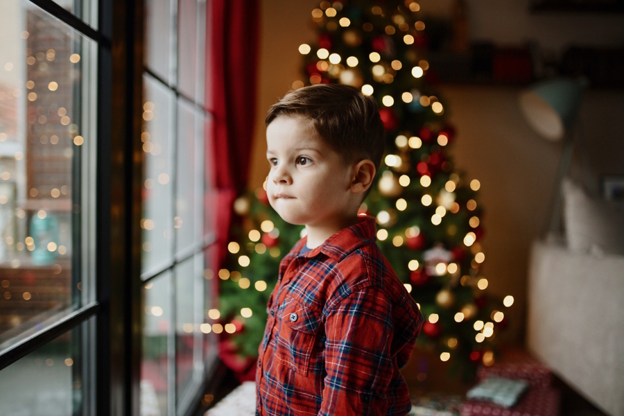 little boy wearing pajamas looking out the window