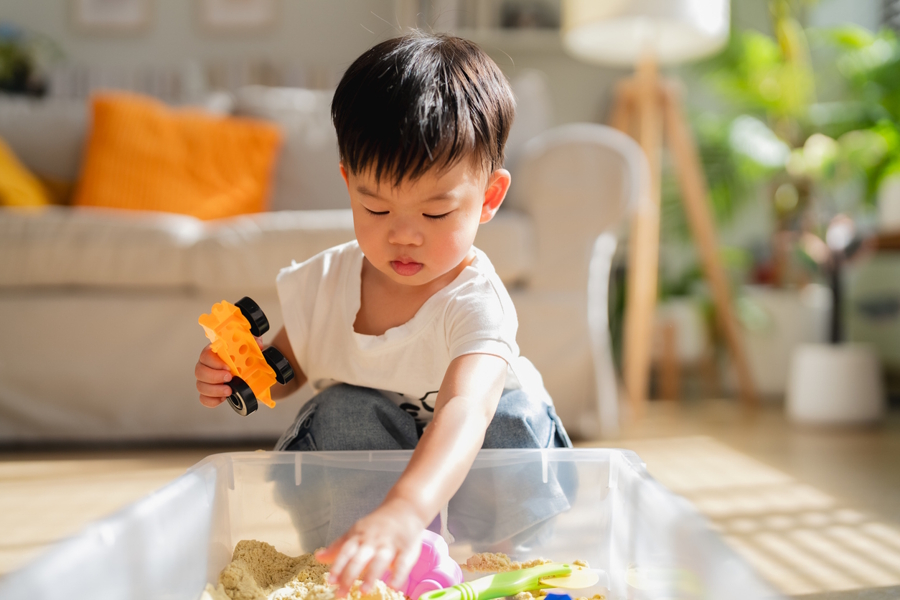 young boy playing in a sensory box