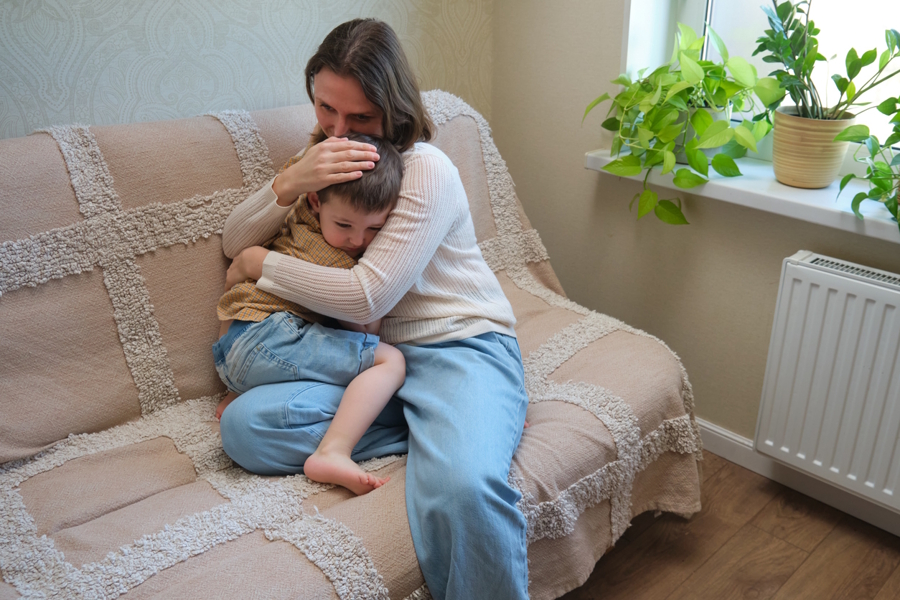 mom sitting on a couch hugging a young boy