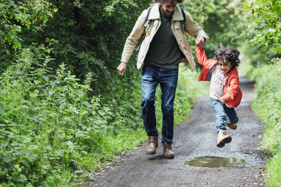 dad and child hiking during the fall and child jumping over a puddle 