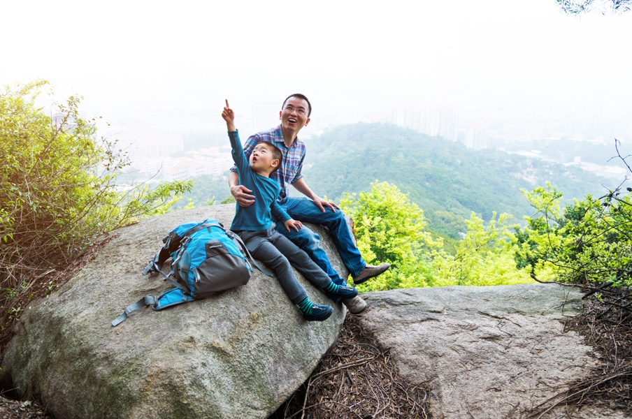dad and son sitting on a rock pointing to something in the sky