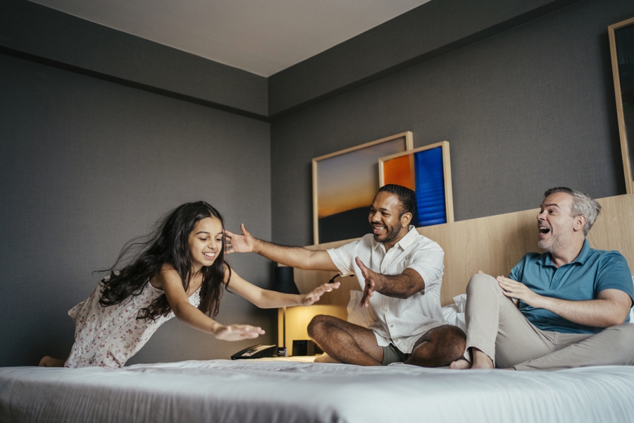 girl diving onto a bed in a hotel room
