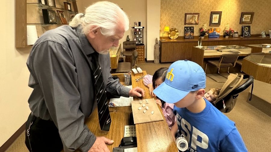 Boy and jeweler looking at rocks on velvet in store