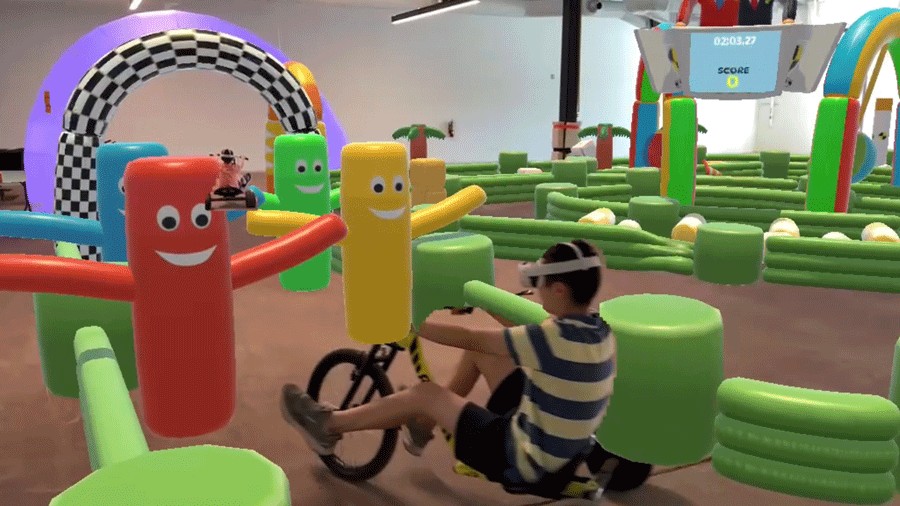 Boys on trike course at DreamPark Seattle with mixed-reality scenes of inflatable crash course