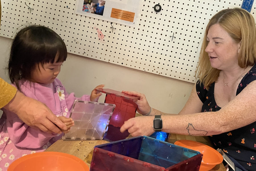 an educator and child building with magnatiles at KidsQuest museum
