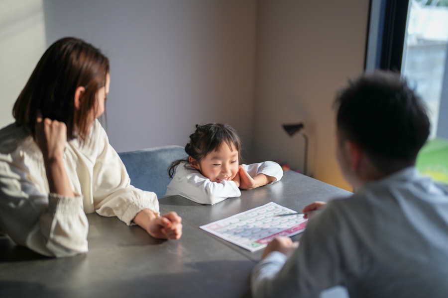 Family sitting at a table looking at a calendar and discussing their new school routine 