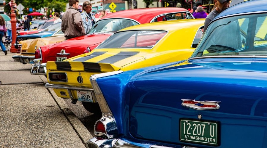Red, yellow and blue vintage cars are lined up at Fenders on Front Street car show.