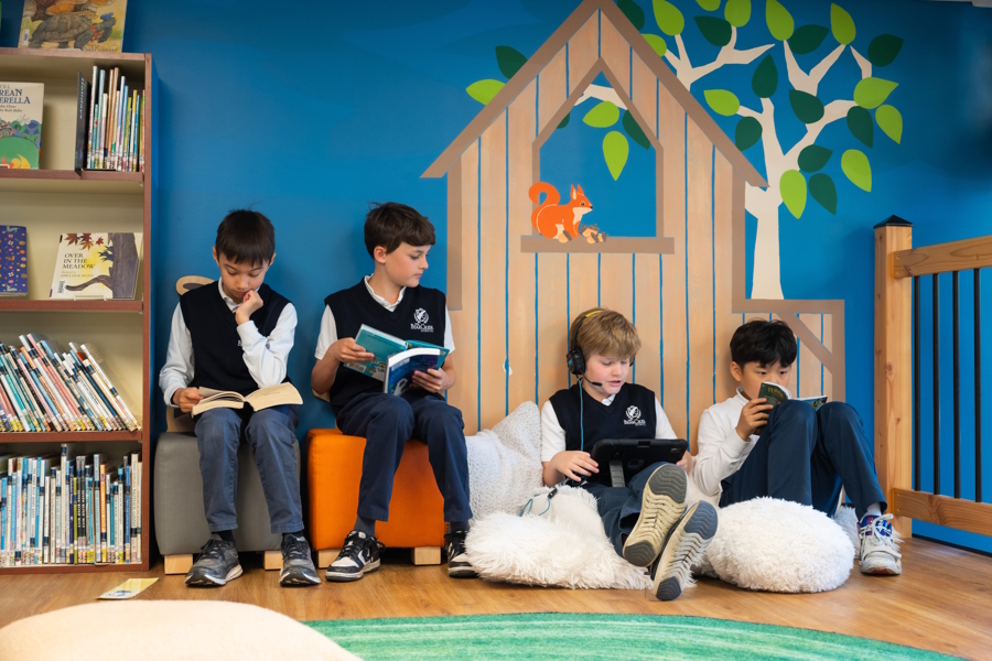 four boys against a wall reading in a library