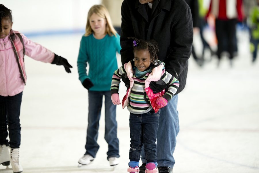 girl and dad at an indoor ice skating rink