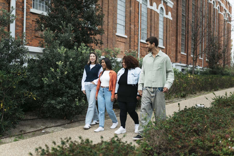 group of people walking down a path a a college campus talking