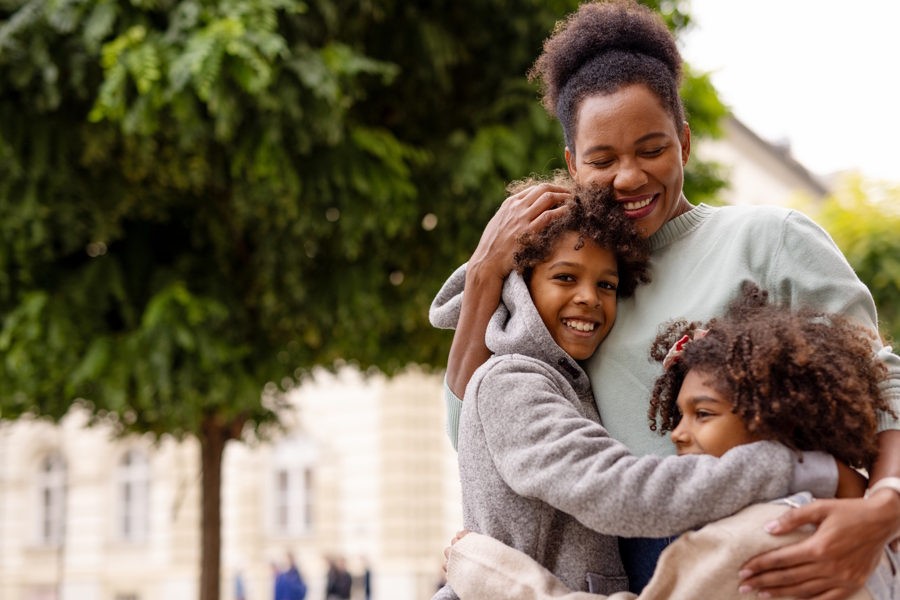 happy mom with son and daughter hugging