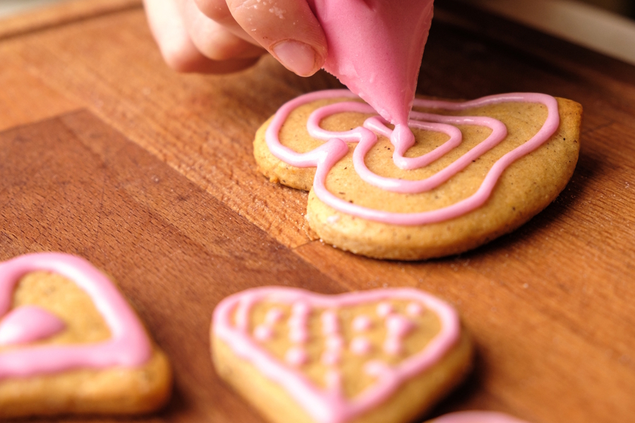 cookie with a hand applying pink frosting