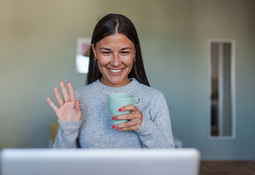 smiling woman waving at coworkers on a video call