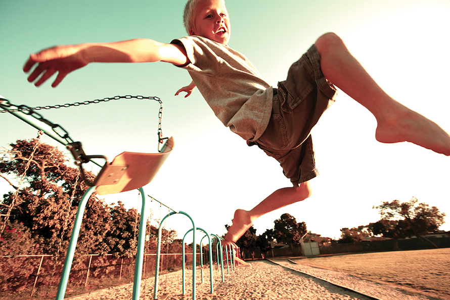boy in mid air leaping off a swing