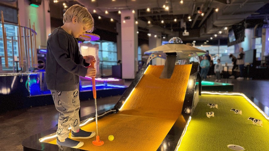 young boy at an indoor mini golf course