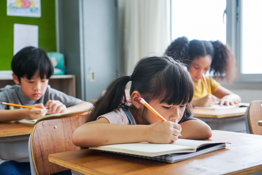 children in a classroom using paper and pencils