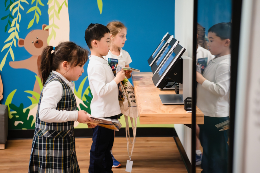 kids checking out book at a library