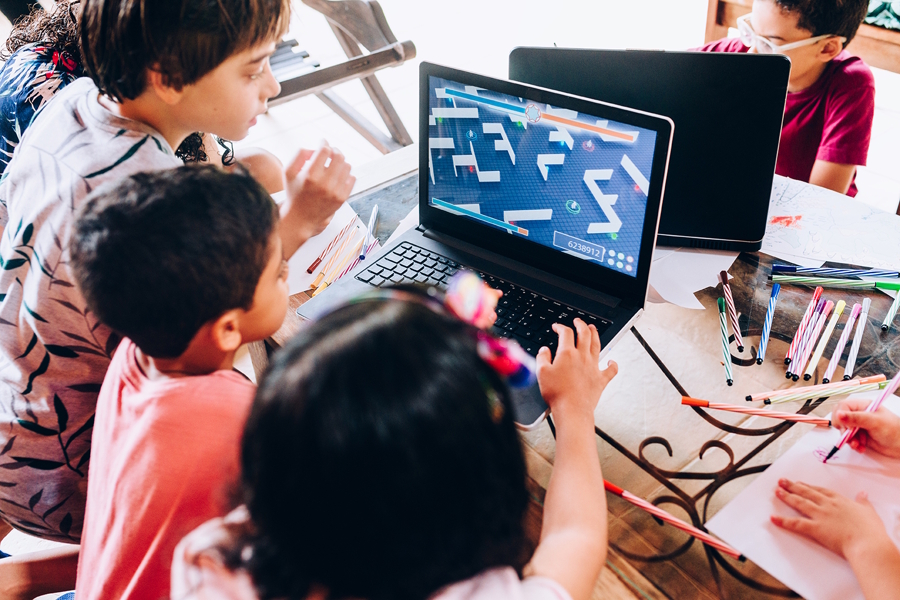 kids in a classroom gathered around a laptop playing and educational game