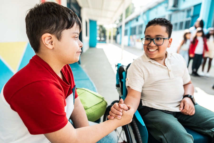 two kids at school shaking hands one child is in a wheelchair