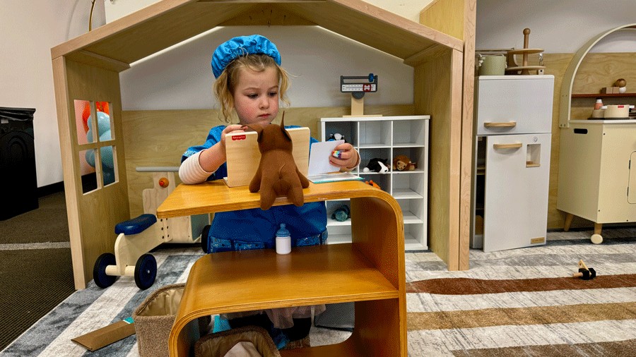 young kid playing doctor at the indoor play space with an animal hospital and costumes for imaginative play